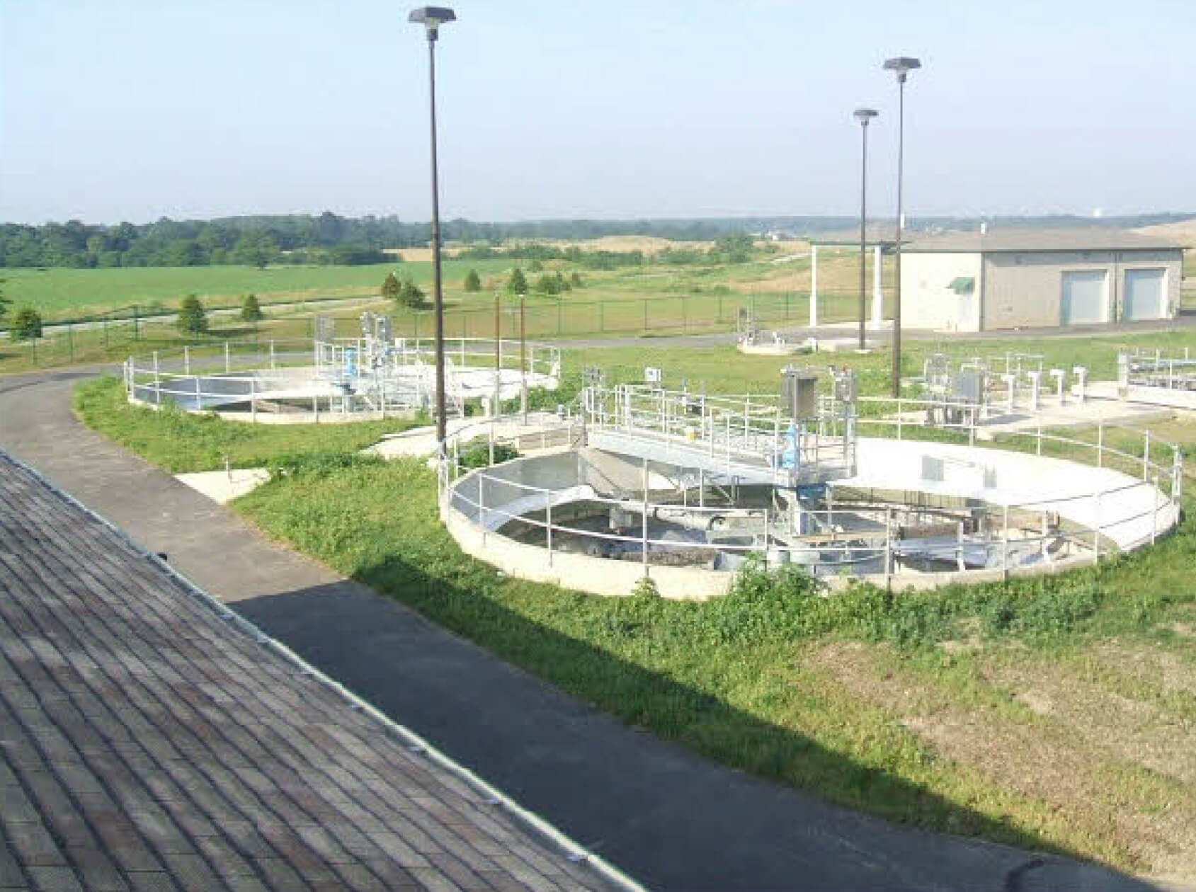 Outdoor wastewater treatment plant with circular treatment basins, utility buildings.