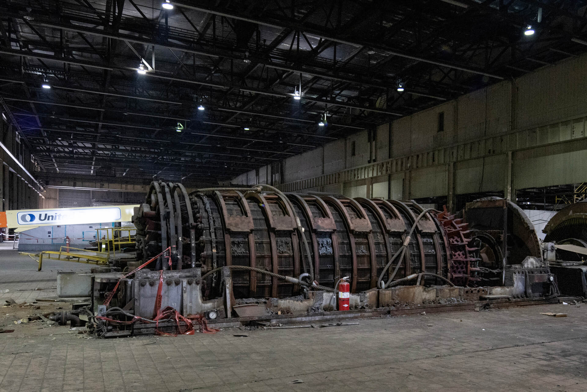Large industrial mining equipment inside a processing facility, with heavy machinery and structural supports.