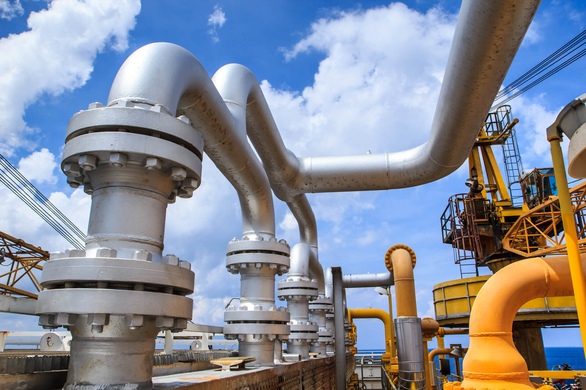Industrial piping and valves at an outdoor processing facility, with metal pipes, gauges and equipment.