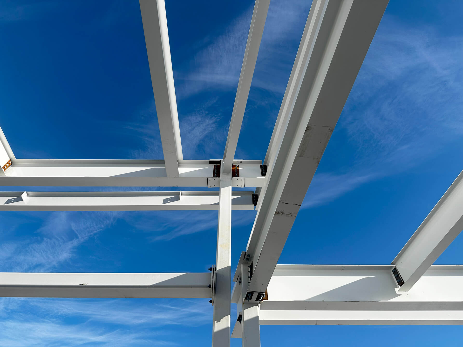 Close-up view of exposed steel beams and structural connections beneath an industrial roof or canopy.