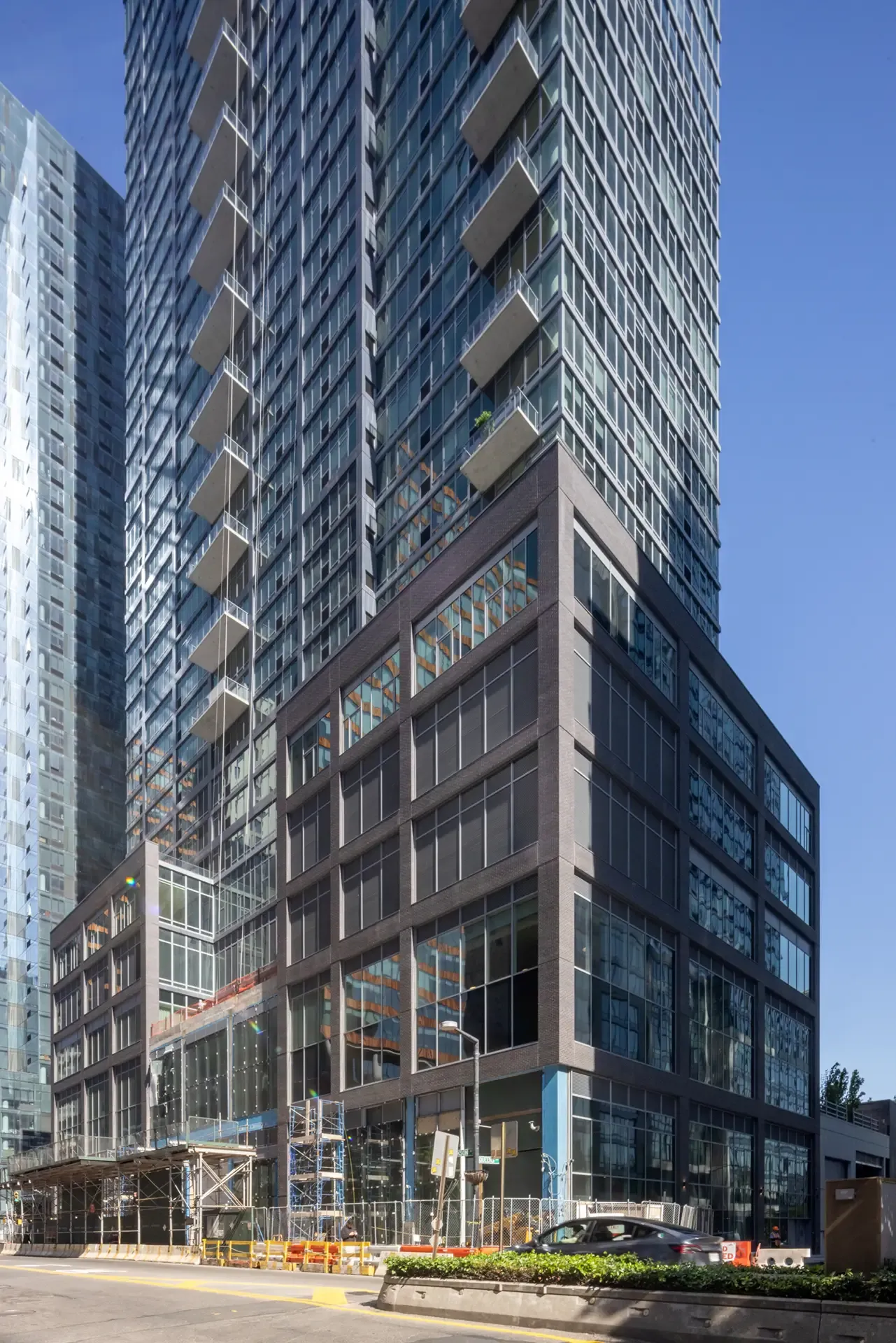 View of The Orchard’s glass tower and multi-story podium, showing the building’s base and balconies.