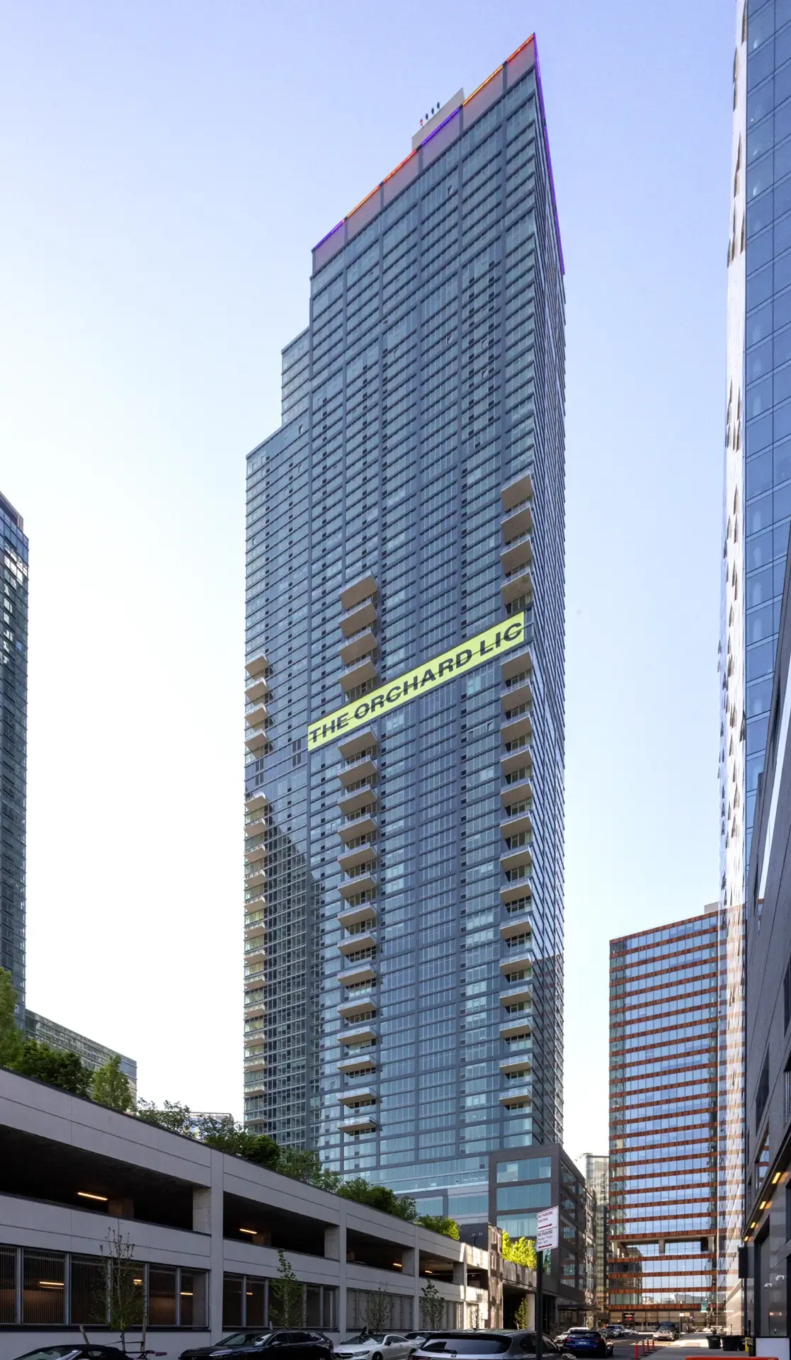 The Orchard’s 69-story residential tower rises above surrounding Long Island City high-rises under a blue sky.
